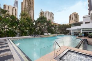 a large swimming pool with palm trees and buildings at Mantra Legends Hotel in Gold Coast