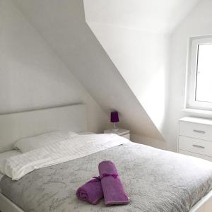 a bed with a pair of purple shoes on it at Lawendowe Domki Dziwnówek in Dziwnówek
