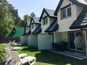 a house with a yard with chairs and a table at Lawendowe Domki Dziwnówek in Dziwnówek