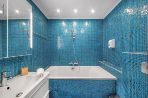 La salle de bains est pourvue de carrelage bleu, d'une baignoire et d'une douche. dans l'établissement NOCNOC - Le Mosaïque, centre Toulouse, à Toulouse