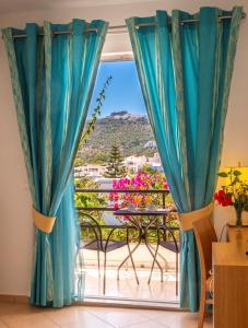 a room with a view of a balcony with blue curtains at Skala Hotel in Skala