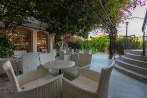 a patio with white chairs and a table and trees at Skala Hotel in Skala