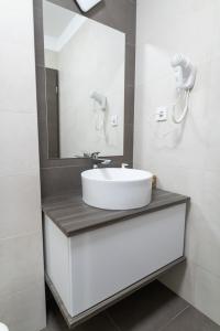 y baño con lavabo blanco y espejo. en Manna Aparthotel, en Jászberény