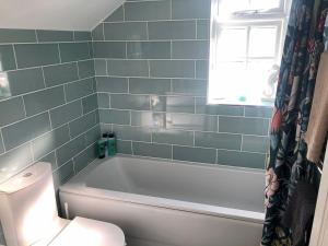 ein Badezimmer mit Badewanne und Toilette und einem Fenster in der Unterkunft Pixie Cottage in Eastbourne + 8 Fotos