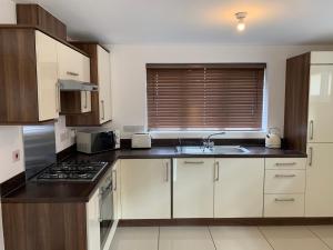 cocina con armarios blancos y fogones en 2 Bed House Waterside Luxury Living, Central Area, en Leicester
