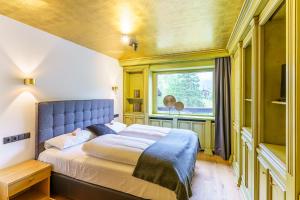 sypialnia z łóżkiem z niebieskim zagłówkiem i oknem w obiekcie Appartement Seefeld Tirol - Luxusappartement Birkenwald w mieście Seefeld in Tirol