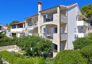 a white apartment building with a balcony and trees at Apartments Tamara in Hvar