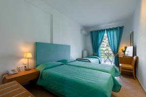 a bedroom with a green bed and a window at Skala Hotel in Skala