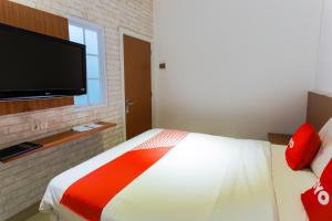 a bedroom with a bed and a flat screen tv at Hotel O Point Inn in Jakarta