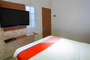SUPER OYO 3109 Point Inn في جاكرتا: غرفة نوم بسرير وتلفزيون بشاشة مسطحة