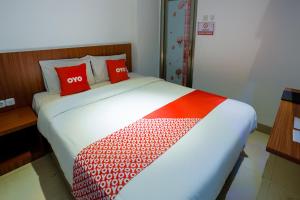 a bedroom with a large bed with red pillows at Hotel O Point Inn in Jakarta