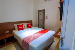 a bedroom with a bed with red pillows on it at Hotel O Point Inn in Jakarta