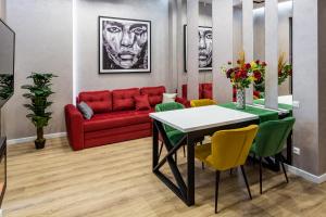 een woonkamer met een rode bank en een tafel en stoelen bij Alfa Apartments 3-кімнатна LUX-квартира у центрі Львова in Lviv