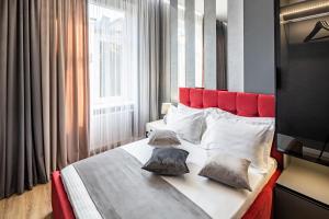 - une chambre avec un grand lit et une tête de lit rouge dans l'établissement Alfa Apartments 3-кімнатна LUX-квартира у центрі Львова, à Lviv