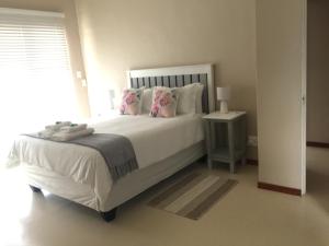 a bedroom with a large white bed with pink pillows at The Vine in Klawer