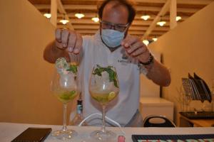un hombre con una máscara frente a dos copas de vino en Kapuhala Sicily en Marzamemi