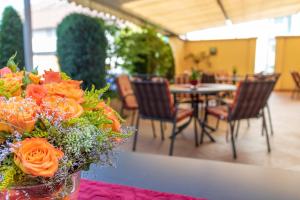 een vaas gevuld met oranje bloemen zittend op een tafel bij Hotel Lamm in Ostfildern