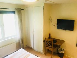 um quarto com uma televisão na parede e uma cadeira em Wisingsö Hotell em Visingsö