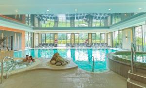 a large swimming pool with two people in a jacuzzi at Sopwell House Hotel in St. Albans