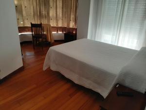 a bedroom with a white bed and a wooden floor at Pensión Vista Alegre in Vigo