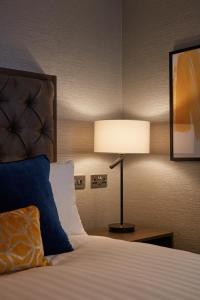 a bedroom with a bed and a lamp at voco Edinburgh - Haymarket, an IHG Hotel in Edinburgh