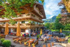 a hotel with people sitting at tables in front of a building at Rasmushof - Hotel Kitzbühel in Kitzbühel