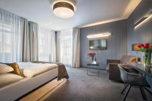 プラハにあるホテル ミュシャのベッドとデスクが備わるホテルルームです。
