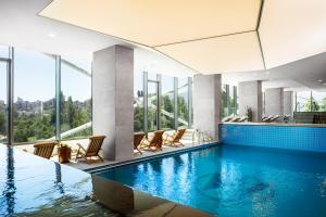 a swimming pool in a building with chairs and windows at Grand Hotel Millennium Sofia - The Most Spacious Rooms in Sofia, Secured Underground Parking in Sofia