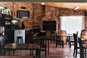 un restaurante con mesas y sillas y una pared de ladrillo en The Lazy Grape Guest Lodge & Spa, en Benoni