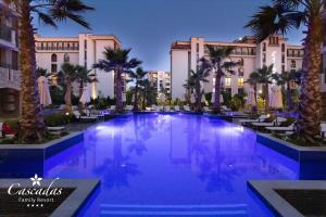 a large swimming pool with palm trees in front of a building at Cascadas Family Resort in Sunny Beach