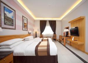 a hotel room with a large bed and a television at Ramada Qurum Beach Hotel in Muscat