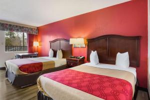 2 Betten in einem Hotelzimmer mit roten Wänden in der Unterkunft Econo Lodge Historic Area in Williamsburg