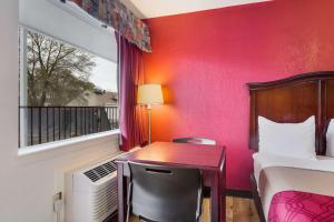 a room with a bed and a desk and a window at Econo Lodge Historic Area in Williamsburg