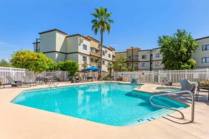 a swimming pool with chairs and a building at Windmill Suites Surprise, Ascend Hotel Collection in Surprise