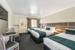 a hotel room with two beds and a desk at Quality Inn Ashby House Tamworth in Tamworth