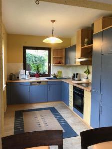 eine große Küche mit blauen Schränken und einem Fenster in der Unterkunft Ferienhaus Morgensonne in Neustadt in Sachsen