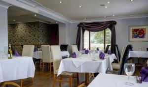 a restaurant with white tables and chairs and a window at Everglades Hotel Widnes in Widnes