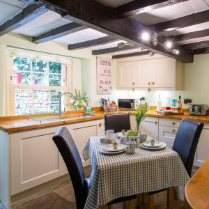 uma cozinha com mesa e cadeiras e uma cozinha com armários brancos em Poppy Cottage em Grassington