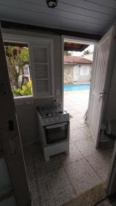 a kitchen with a stove and a door to a pool at Bertioga litoral in Bertioga