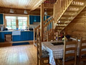 cocina con armarios azules, mesa y escaleras en Riverside log cabin, en Ballyconnell