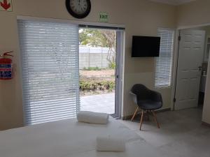 1 dormitorio con mesa, silla y reloj en Sharon's House: Modern Self-Catering rooms, en Ciudad del Cabo