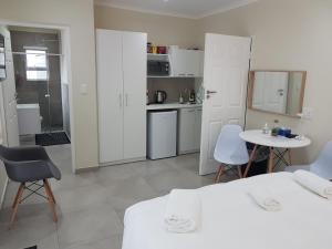 cocina con armarios blancos, mesa y sillas en Sharon's House: Modern Self-Catering rooms, en Ciudad del Cabo