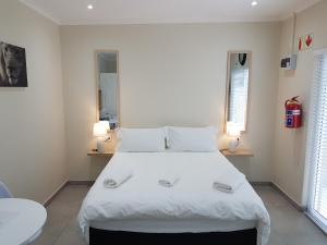 a bedroom with a large white bed with two lamps at Sharon's House: Modern Self-Catering rooms in Cape Town