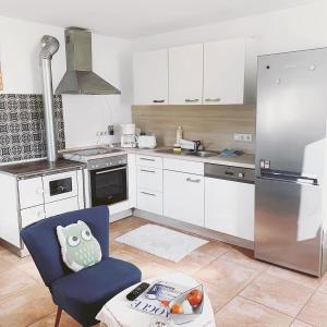 a kitchen with white cabinets and a blue chair at La Toskana Apartment Ihr Rückzugsort am Regen in Zeitlarn