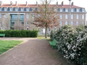 a green park bench in front of a large building at Auberge de Jeunesse HI Amiens in Amiens