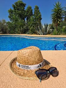a straw hat and sunglasses sitting next to a swimming pool at Sueño Grande in Lliber