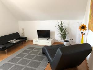 a living room with a black couch and a tv at FeWo Kerstin Rossbacher in Solingen