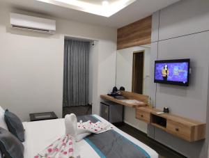 um quarto com uma cama e uma televisão na parede em PARK IRIS HOTELS, MG Road em Vijayawāda