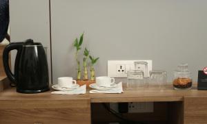 a counter with a coffee pot and cups and glasses at PARK IRIS HOTELS, MG Road in Vijayawāda
