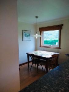 ein Esszimmer mit einem Tisch und einem Fenster in der Unterkunft Strathspey in Kyleakin